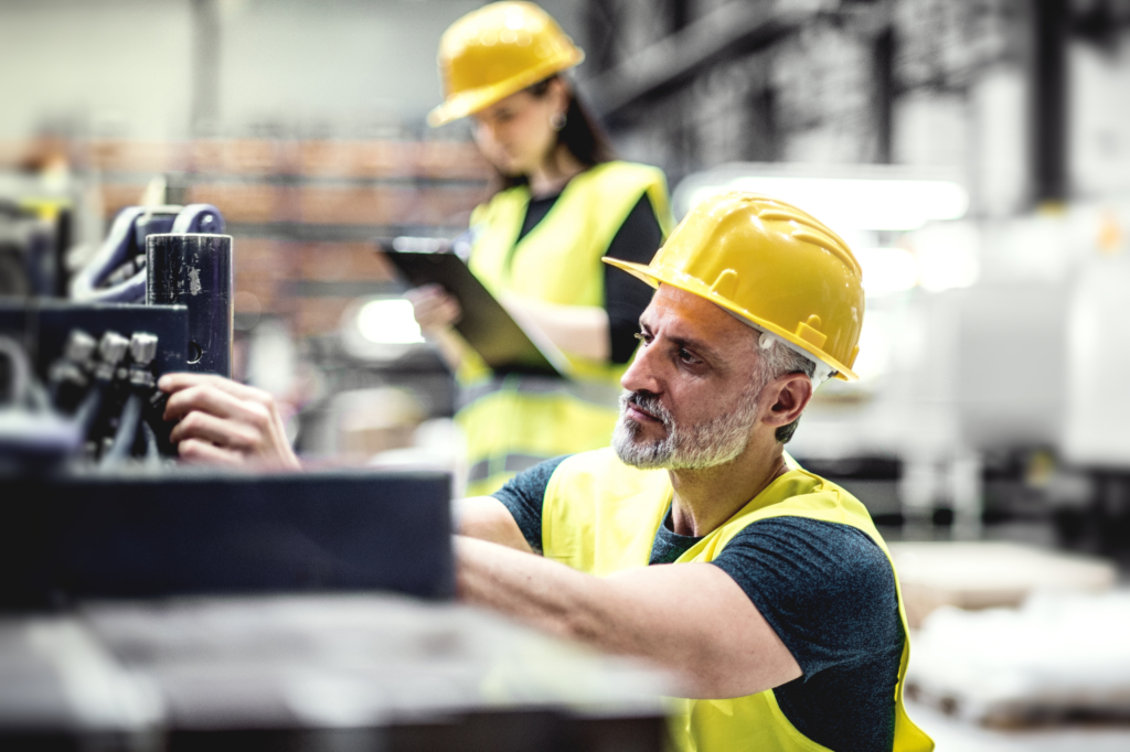 EHS man in focus in factory woman blur clipboard